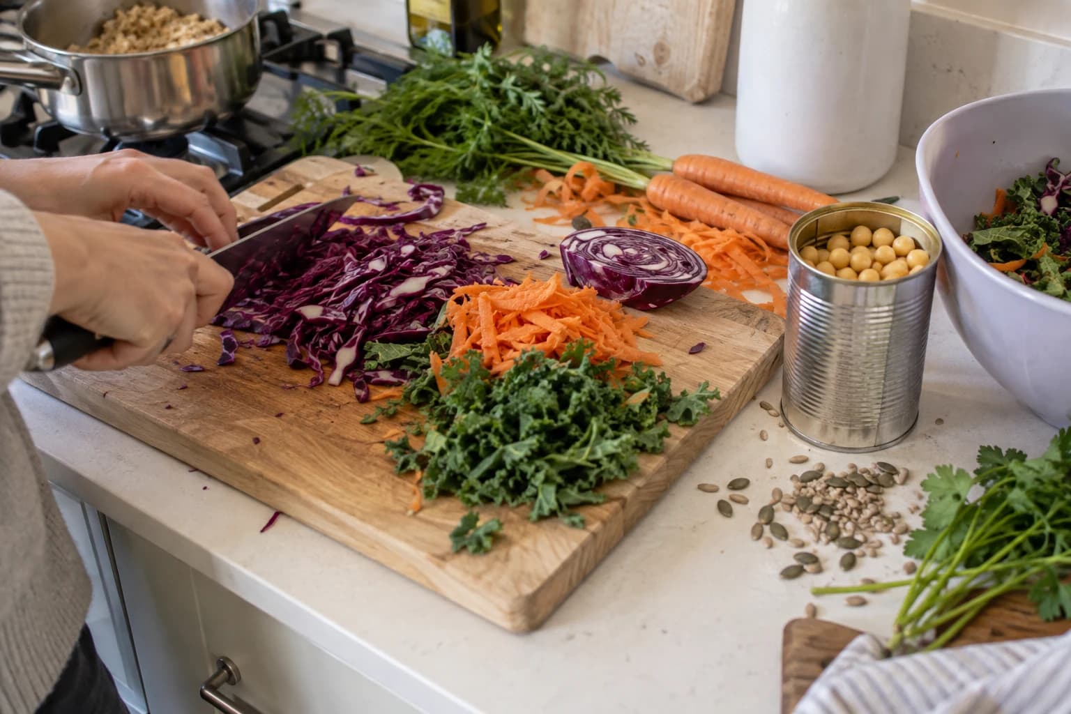 Vegetables, chickpeas, grains, herbs and seeds being prepared together on a working counter