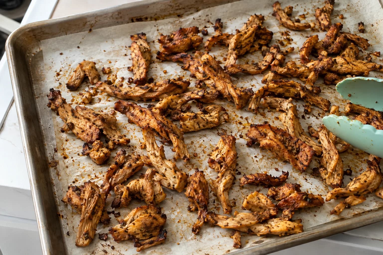 Irregular garlic and oregano soy curls browned across a used sheet pan