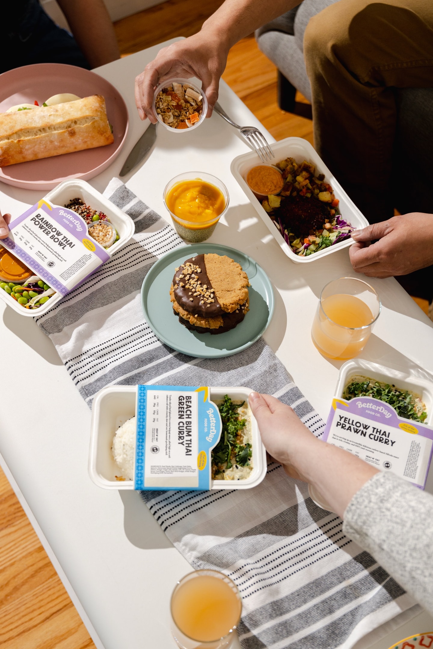 A table spread of labelled BetterDay meals, cookies, and drinks