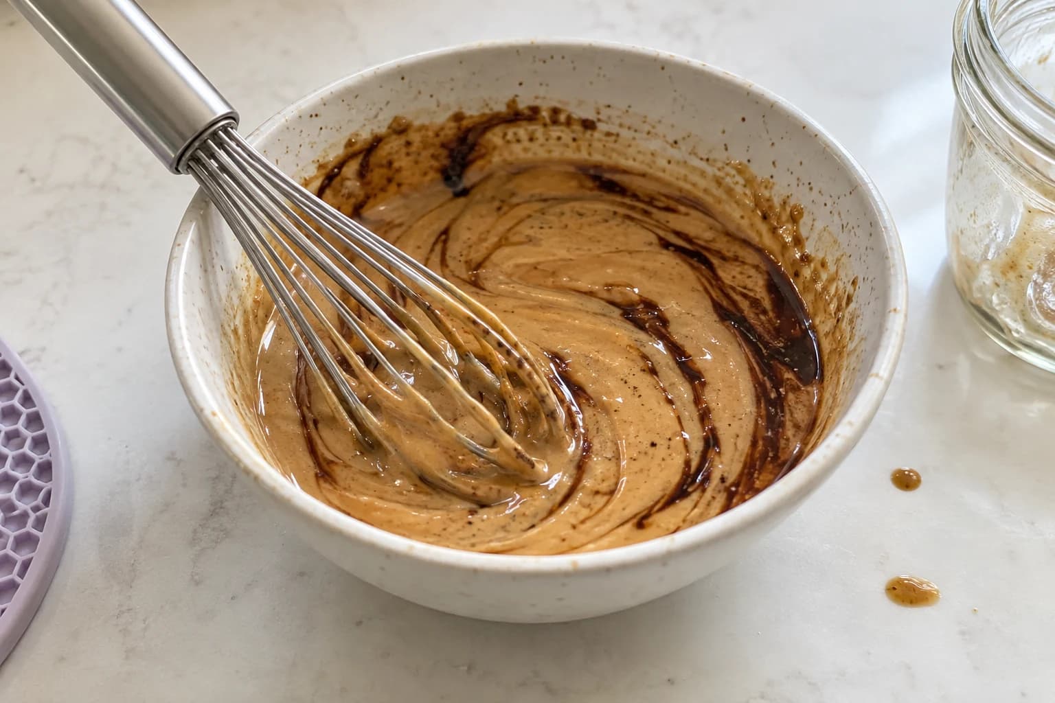 Balsamic and tahini being whisked together in a small ceramic bowl